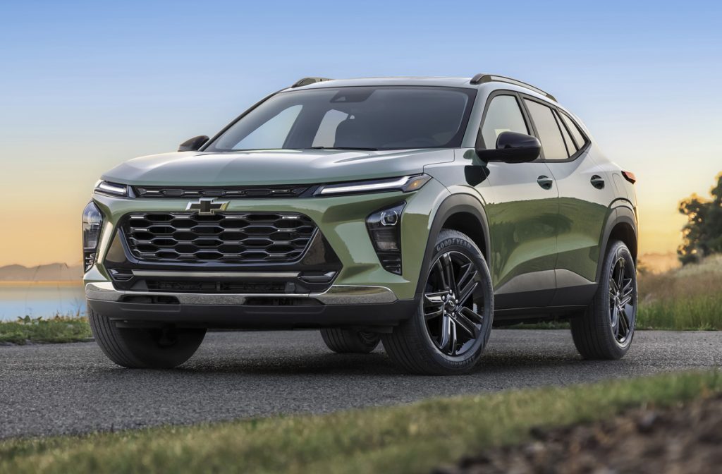 Front 3/4 view of 2025 Chevrolet Trax ACTIV in Cacti Green parked on a road in front of a lake. Pre-production model shown. Actual production model may vary.