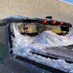 2026 GMC Hummer Pickup in Meteorite Metallic, covered in snow, lights on,