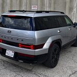 2026 Hyundai Santa Fe Hybrid Calligraphy in Shimmering Silver, rear 3/4 view, taillights on,