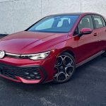 2026 Volkswagen GTI Autobahn in Kings Red, front 3/4 view, headlamps on,