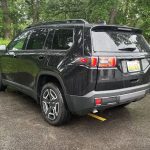 2026 Jeep Cherokee Laredo in Diamond Black Crystal, rear 3/4 view, rain, taillights on,