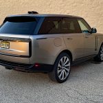 2026 Land Rover Range Rover SE in Batumi Gold, rear 3/4 view, sunset, magic hour,