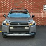 2026 Toyota RAV4 Woodland PHEV in Urban Rock, front end, headlights on, brick wall,