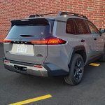 2026 Toyota RAV4 Woodland PHEV in Urban Rock, rear 3/4 view, taillights on,
