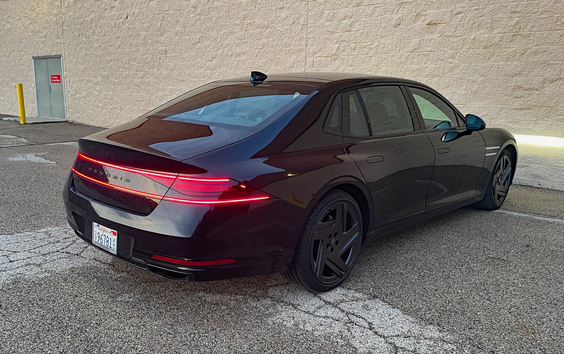 2026 Genesis G90 Prestige Black, rear 3/4 view, taillights on,